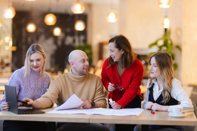 Model zarządzania współpracą nauka-biznes w województwie pomorskim i jego wdrożenie | Uniwersytet WSB Merito w Gdańsku: Studenci pracują w grupie w przestrzeni o ciepłym pomarańczowym świetle