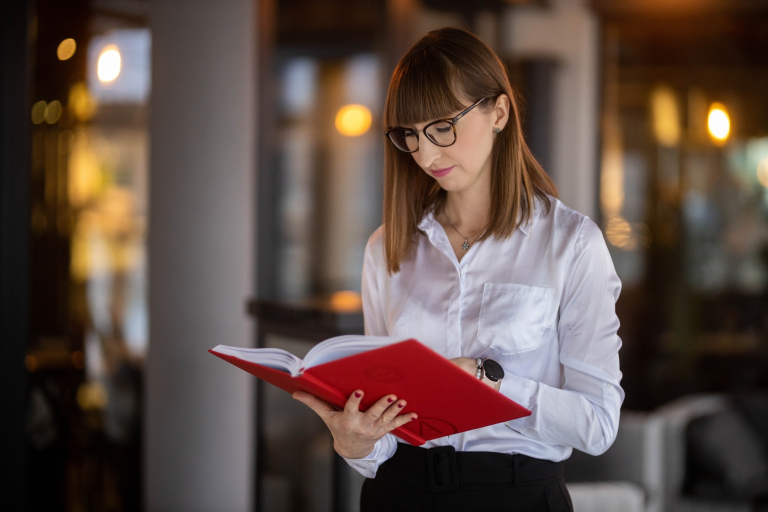 Digital Marketing Masterclass | Studia podyplomowe w Gdańsku | Uniwersytet WSB Merito w Gdańsku: Studentka w białej koszuli i okularach z książką w ręku