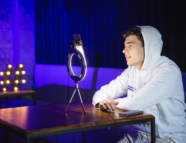 Produkcja audiowizualna w mediach cyfrowych | Studia I stopnia w Gdańsku | Uniwersytet WSB Merito w Gdańsku: Student przy nagrywce na komórce