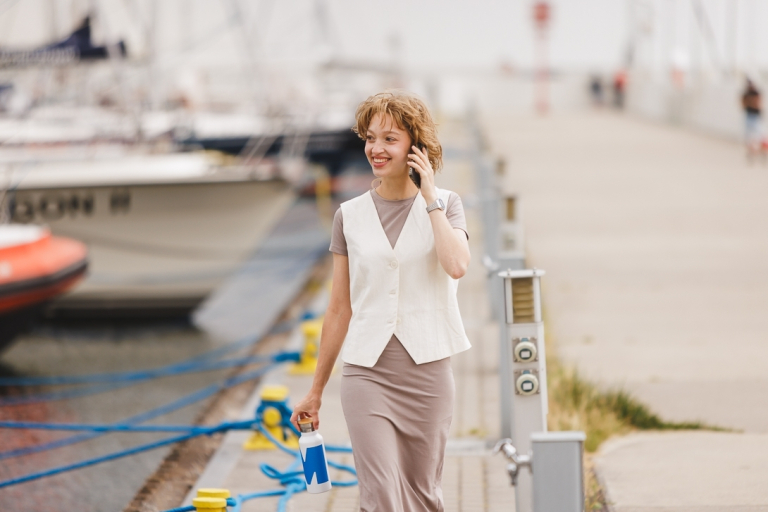 Nutripsychiatria | Studia podyplomowe w Gdańsku | Uniwersytet WSB Merito w Gdańsku: Studentka rozmawia przez telefon idąc przez gdyńską marinę