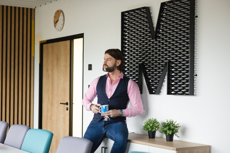 Analiza biznesowa wspomagana AI | Studia podyplomowe w Gdańsku | Uniwersytet WSB Merito w Gdańsku: Mężczyzna w sali przy sygnecie Merito