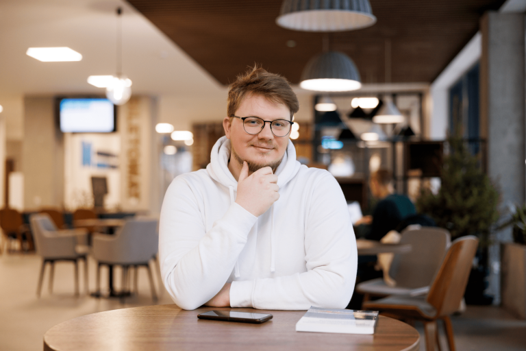 Analityk finansowy i rynkowy | Studia I stopnia w Gdańsku | Uniwersytet WSB Merito w Gdańsku: Student w białej bluzie w holu przy stoliku 
