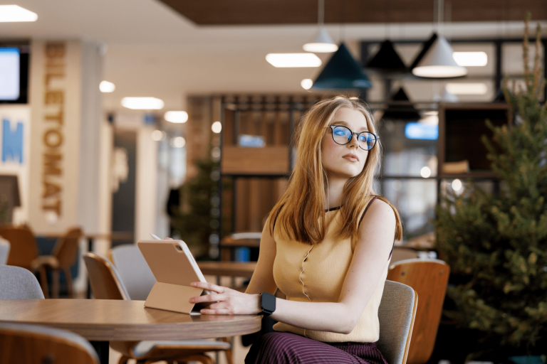 Marketing i komunikacja społeczna | Studia I stopnia w Gdańsku | Uniwersytet WSB Merito w Gdańsku: Studentka z tabletem przy biurku w holu 