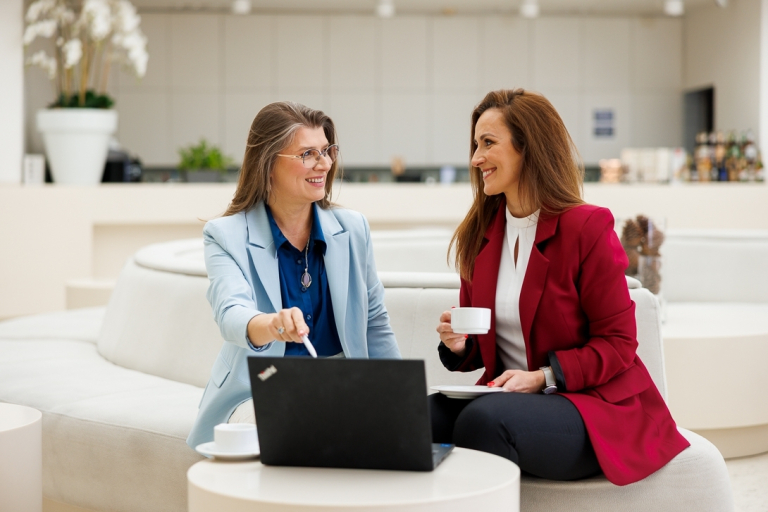 AI Developer & Vibe Coding – nowoczesne środowiska programowania z AI | Studia podyplomowe w Gdańsku | Uniwersytet WSB Merito w Gdańsku: Rozmowa kobiet przy laptopie w jasnej przestrzeni