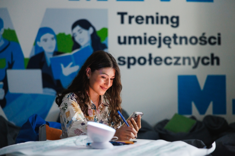 Transport autonomiczny i bezzałogowy | Studia I stopnia w Gdańsku | Uniwersytet WSB Merito w Gdańsku: Studentka przy banerze treningu umiejętności społecznych