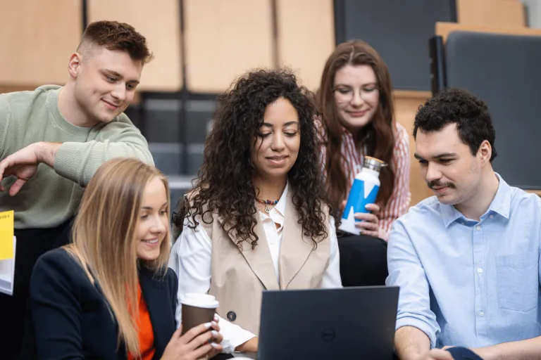 Programowanie desktop apps | Uniwersytet WSB Merito w Gdańsku: Studenci zebrani wokół laptopa na auli