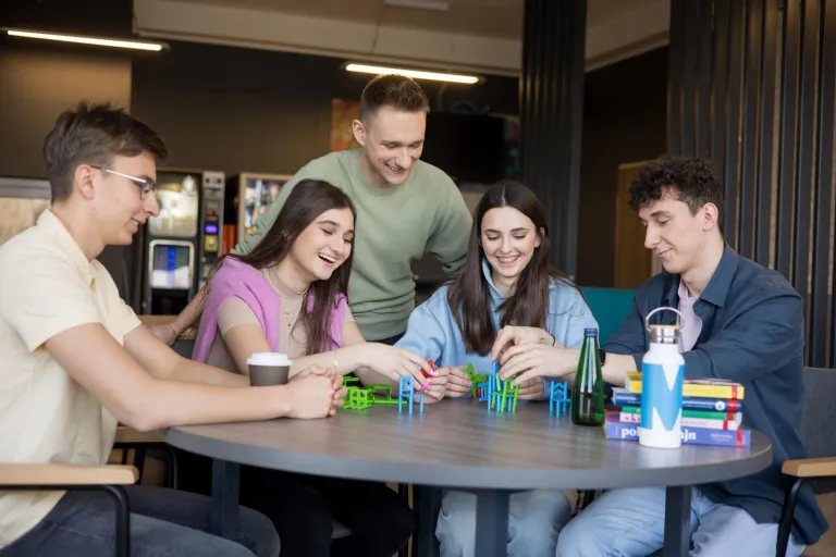 Terapia pedagogiczna z elementami integracji sensorycznej | Studia I stopnia w Gdańsku | Uniwersytet WSB Merito w Gdańsku: Studenci siedzą na przerwie i układają konstrukcję z zabawkowych krzesełek