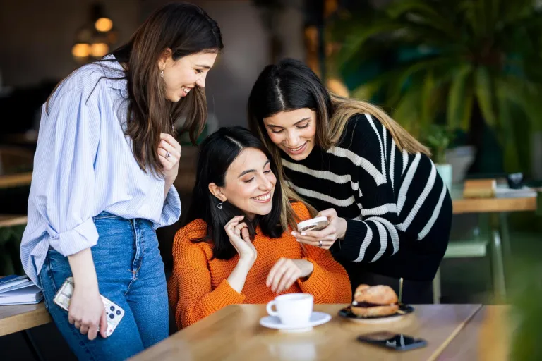 Marketing i sprzedaż | Uniwersytet WSB Merito w Gdańsku: Studentki w kawiarni rozmawiają na temat tego, co widzą w komórce
