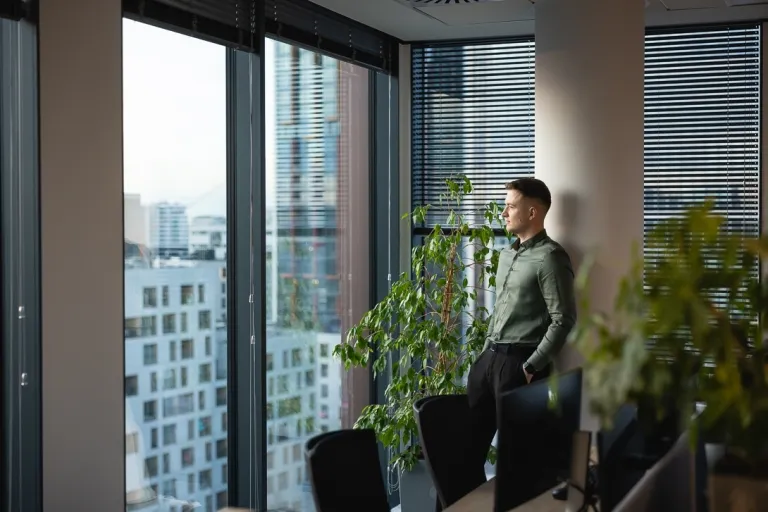 Psychoseksuologia | Uniwersytet WSB Merito w Gdańsku: Zdjęcie mężczyzny patrzącego przez dużą szybę na budynki