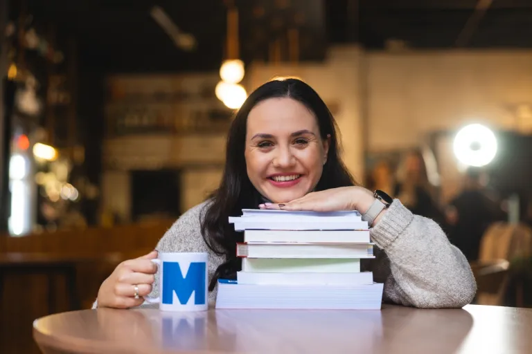 Administrowanie zasobami energetycznymi | Studia II stopnia ze studiami podyplomowymi  | Uniwersytet WSB Merito w Gdańsku: Portret kobiety, która opiera się brodą o książki, uśmiecha się