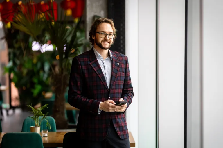 Administracja i biznes | Studia II stopnia ze studiami podyplomowymi w Gdańsku | Uniwersytet WSB Merito w Gdańsku: Zdjęcie biznesowe studenta w garniturze z komórką w rękach