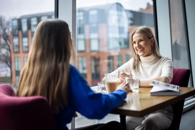 Pedagogika szkoły z integracją imigrantów | Studia II stopnia ze studiami podyplomowymi  | Uniwersytet WSB Merito w Gdańsku: Studentki rozmawiają podczas wizyty w kawiarni. Siedzą przy stoliku przy kawie