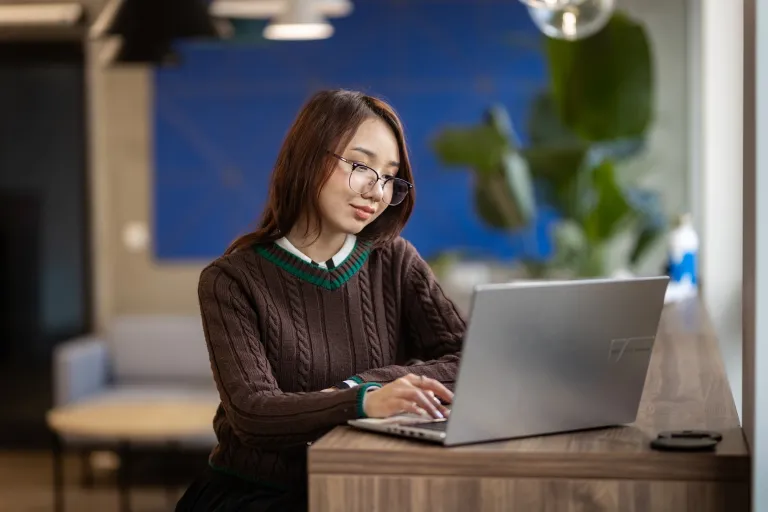 Zarządzanie zasobami ludzkimi – z certyfikatem FU | Studia I stopnia w Gdańsku | Uniwersytet WSB Merito w Gdańsku: Studentka o azjatyckiej urodzinie przy laptopie