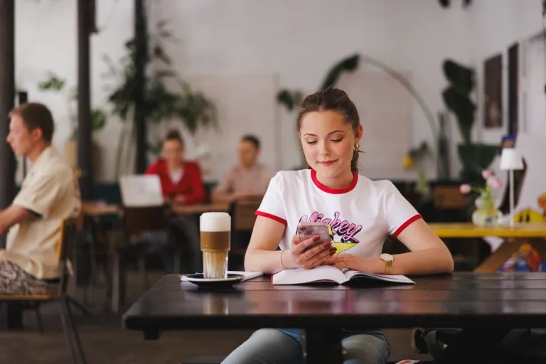 Komunikacja cyfrowa i media kreatywne | Studia II stopnia w Gdańsku | Uniwersytet WSB Merito w Gdańsku: Studentka w kawiarni z kawą i przy otwartej książce