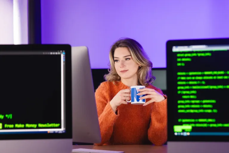 Biały wywiad | Studia I stopnia w Gdańsku | Uniwersytet WSB Merito w Gdańsku: Studentka przy monitorach i z kubkiem w ręku