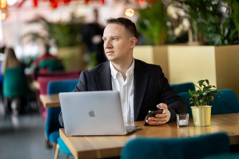 Psychologia w zarządzaniu – z certyfikatem FU | Studia II stopnia ze studiami podyplomowymi  | Uniwersytet WSB Merito w Gdańsku: Student w kawiarni z laptopem i komórką w ręku