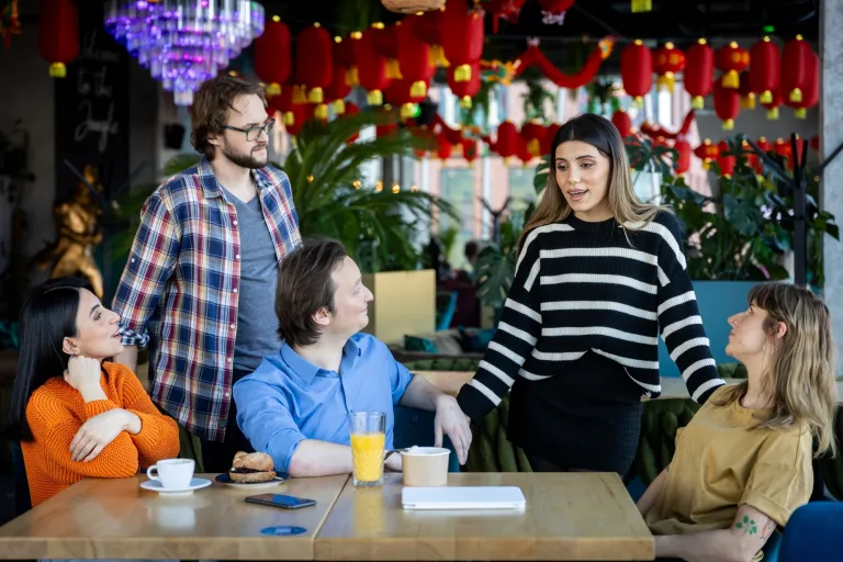 Prompting i optymalizacja systemów AI | Studia I stopnia w Gdańsku | Uniwersytet WSB Merito w Gdańsku: Studenci w kawiarni podczas rozmowy w większej grupie