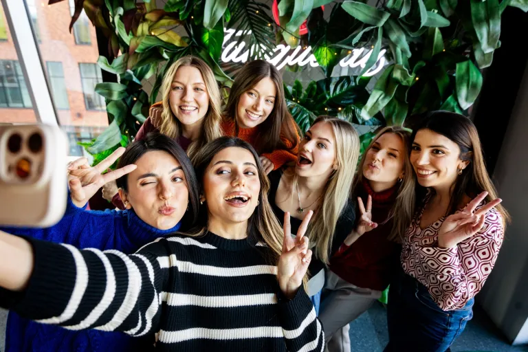 Film marketingowy w e-commerce | Studia I stopnia w Gdańsku | Uniwersytet WSB Merito w Gdańsku: Studenci WSB Merito w Gdańsku robią sobie wspólne zdjęcie na tle roślin