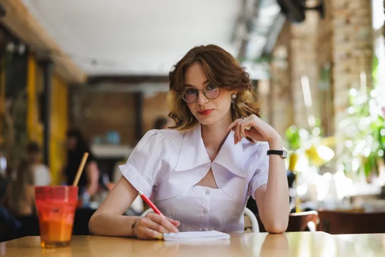 Film marketingowy w e-commerce | Studia I stopnia w Gdańsku | Uniwersytet WSB Merito w Gdańsku: Studentka przy notatkach i napoju w kawiarni 