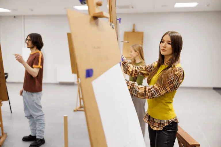 Pedagogika | Studia I stopnia w Gdańsku | Uniwersytet WSB Merito w Gdańsku: Studentka rysuje przy sztaludze