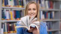 Studentka w bibliotece z książką