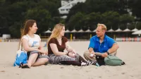 Bezpieczeństwo finansowe i celno-skarbowe państwa | Studia I stopnia w Gdyni | Uniwersytet WSB Merito Gdynia: Studenci siedzą na piasku na plaży