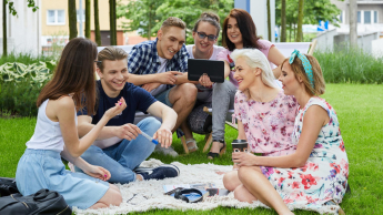 Lektor w szkole językowej | Studia I stopnia w Gdyni | Uniwersytet WSB Merito Gdynia: Studenci na trawie przed budynkiem