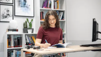 Rachunkowość i finanse przedsiębiorstw | Studia I stopnia w Gdyni | Uniwersytet WSB Merito Gdynia: Dziewczyna siedzi w przestrzeni biurowej i robi notatki
