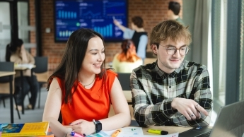 Studentka i student siedzą wspólnie przy biurku. 