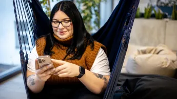 Energetyka wiatrowa | Studia podyplomowe w Gdyni | Uniwersytet WSB Merito Gdynia: Studentka siedzi na hamaku i przegląda telefon