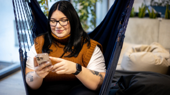 Energetyka wiatrowa | Studia podyplomowe w Gdyni | Uniwersytet WSB Merito Gdynia: Studentka siedzi na hamaku i przegląda telefon