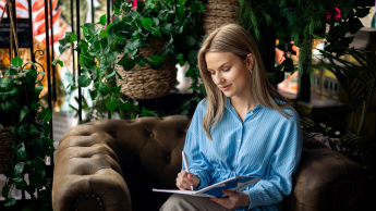 Studentka siedzi na fotelu i pisze w zeszycie