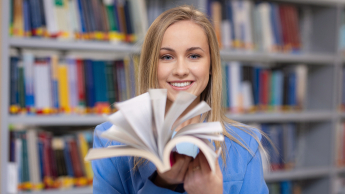 Studentka w bibliotece z książką