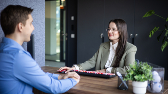 Trener języków obcych | Studia podyplomowe w Gdyni | Uniwersytet WSB Merito Gdynia: Zdjęcie kobiety rozmawiającej z mężczyzną w sprawach służbowych