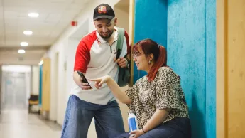 Podatki i doradztwo podatkowe | Studia II stopnia w Gdyni | Uniwersytet WSB Merito Gdynia: Studenci na korytarzu Uniwersytetu w Gdyni, sprawdzają informacje w komórce