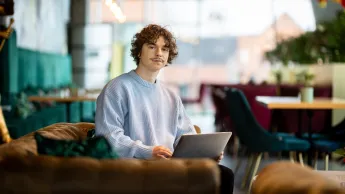 Windykacja i zarządzanie wierzytelnościami | Studia podyplomowe w Gdyni | Uniwersytet WSB Merito Gdynia: Student w kawiarni przy laptopie