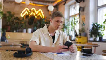 Psychologia transportu | Studia podyplomowe w Gdyni | Uniwersytet WSB Merito Gdynia: Student w kawiarni przy komórce