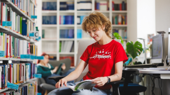 Finanse i rachunkowość | Studia I stopnia w Gdyni | Uniwersytet WSB Merito Gdynia: Studentka w bibliotece przegląda książkę 