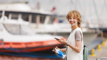 Marketing i sprzedaż | Studia I stopnia w Gdyni | Uniwersytet WSB Merito Gdynia: Studentka przy żaglówkach z komórką w ręku