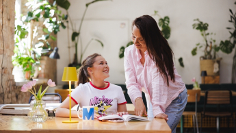 Coaching rozwoju zawodowego i osobistego | Studia I stopnia w Gdyni | Uniwersytet WSB Merito Gdynia: Dziewczyna pochyla się nad stołem przy, którym siedzi studentka