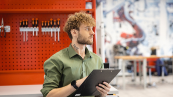 Student w laboratorium, za nim widać klucze