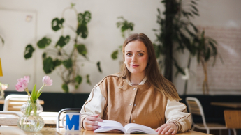 Studentka siedzi przy książce i kubku w kawiarni 