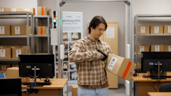 Student w magazynie z kartonami 