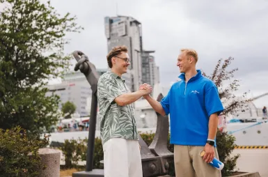 Zapraszamy na sesję, ale spokojnie – tylko zdjęciową! | Aktualności | Uniwersytet WSB Merito Gdynia: Studenci wymieniają sobie uścisk dłoni przy Sea Tower w Gdyni