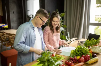 Aktualności | Uniwersytet WSB Merito Gdynia: Student i studentka nad książką, wokół warzywa i owoce
