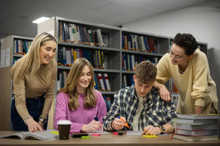Terapia pedagogiczna z elementami arteterapii | Studia I stopnia w Gdyni | Uniwersytet WSB Merito Gdynia: grupa osób pracująca przy biurku w bibliotece