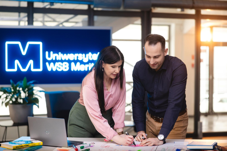 Pośrednictwo pracy | Uniwersytet WSB Merito Gdynia: dwie osoby stojące przy stole pracujące nad projektem