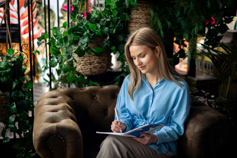 Podatki i doradztwo podatkowe | Studia I stopnia w Gdyni | Uniwersytet WSB Merito Gdynia: Studentka siedzi na fotelu i pisze w zeszycie