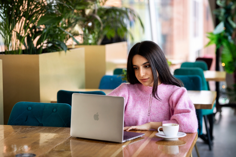 Finanse i rachunkowość - studia 3 semestralne | Studia II stopnia w Gdyni | Uniwersytet WSB Merito Gdynia: Studentka siedzi w kawiarni z laptopem i kawą.