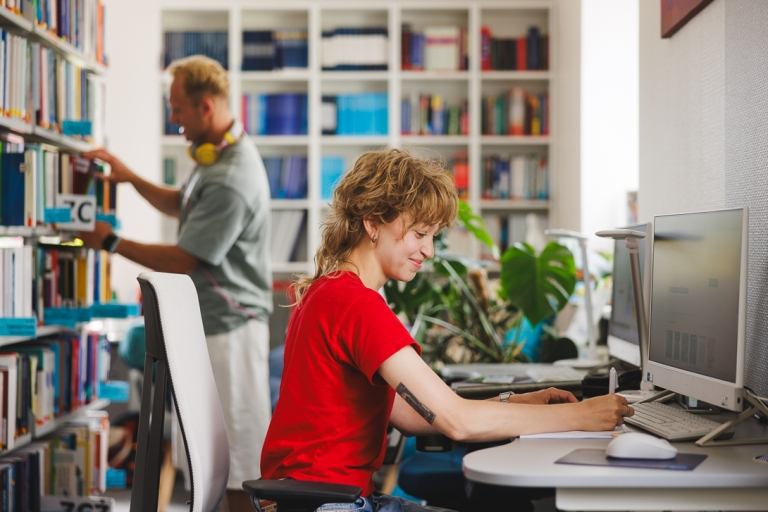 Pełnomocnik ds. osób z niepełnosprawnościami | Uniwersytet WSB Merito Gdynia: Studentka przy komputerze w bibliotece
